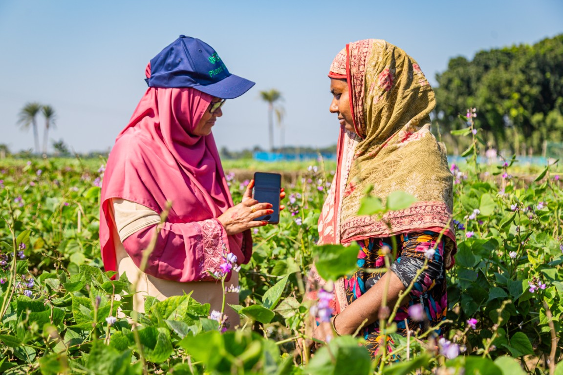2 Women in a field looking at a smart phone