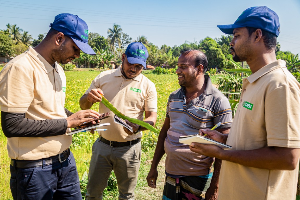 4 People in a field, 3 of which are wearing CABI uniforms