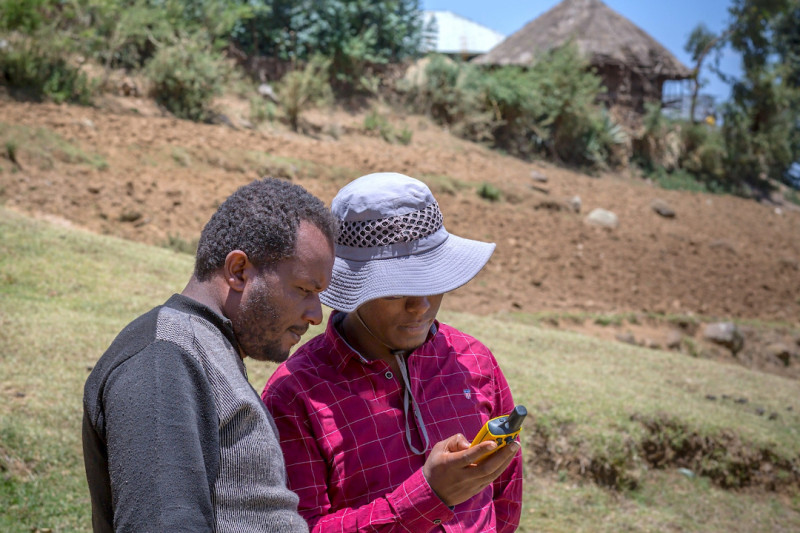 Two agriculturists stood in field using a hand-held data collection device